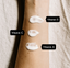 Close-up of arm with three white cream samples, labeled Vitamin E, Vitamin C, and Vitamin A, demonstrating key skincare ingredients