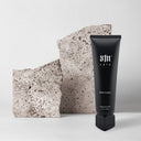 S1N Care fragrance-free body lotion tube next to textured stone blocks on a light background